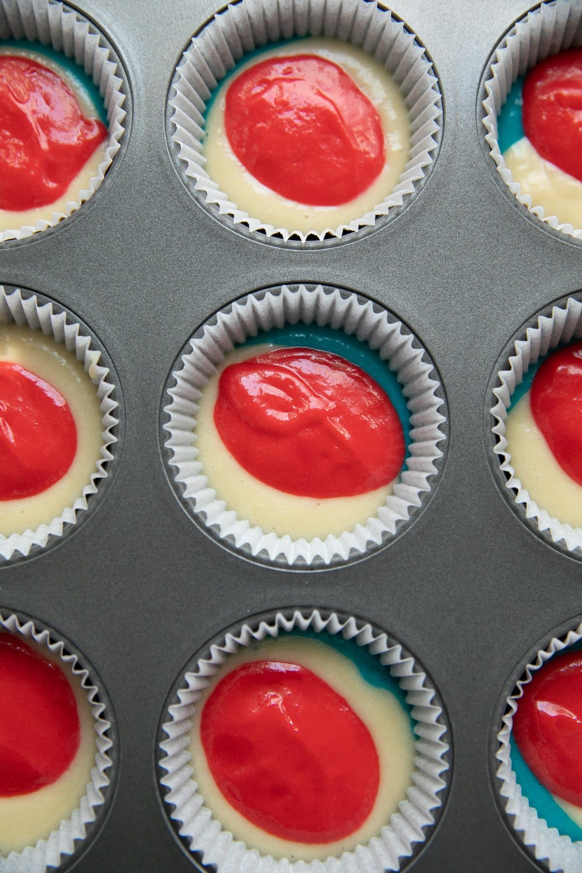 red, white and blue batter in muffin tins