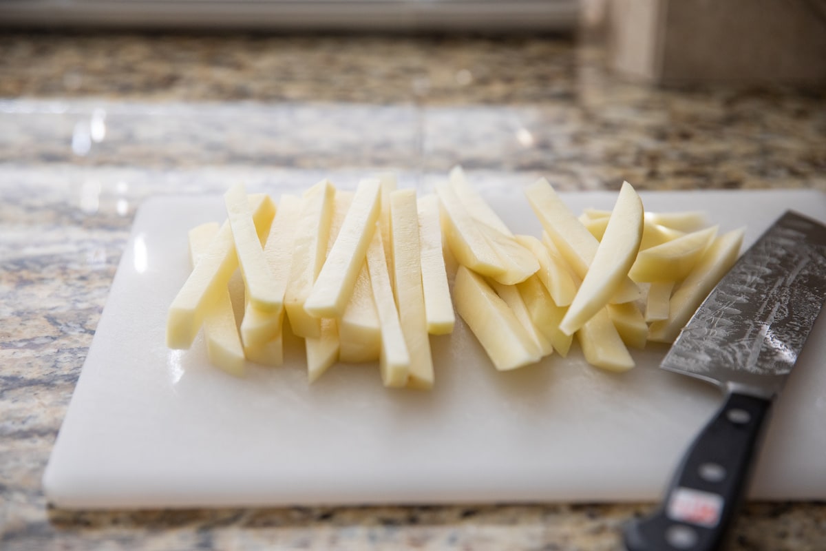 potato cut into fries on cutting board