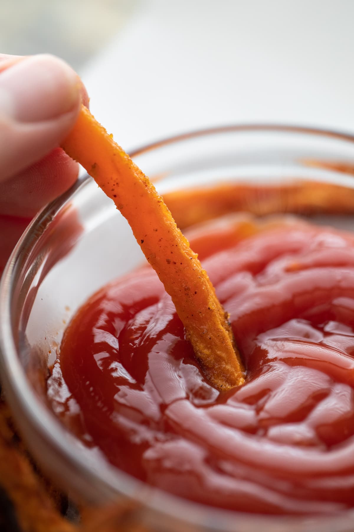 dipping sweet potato fry into ketchup