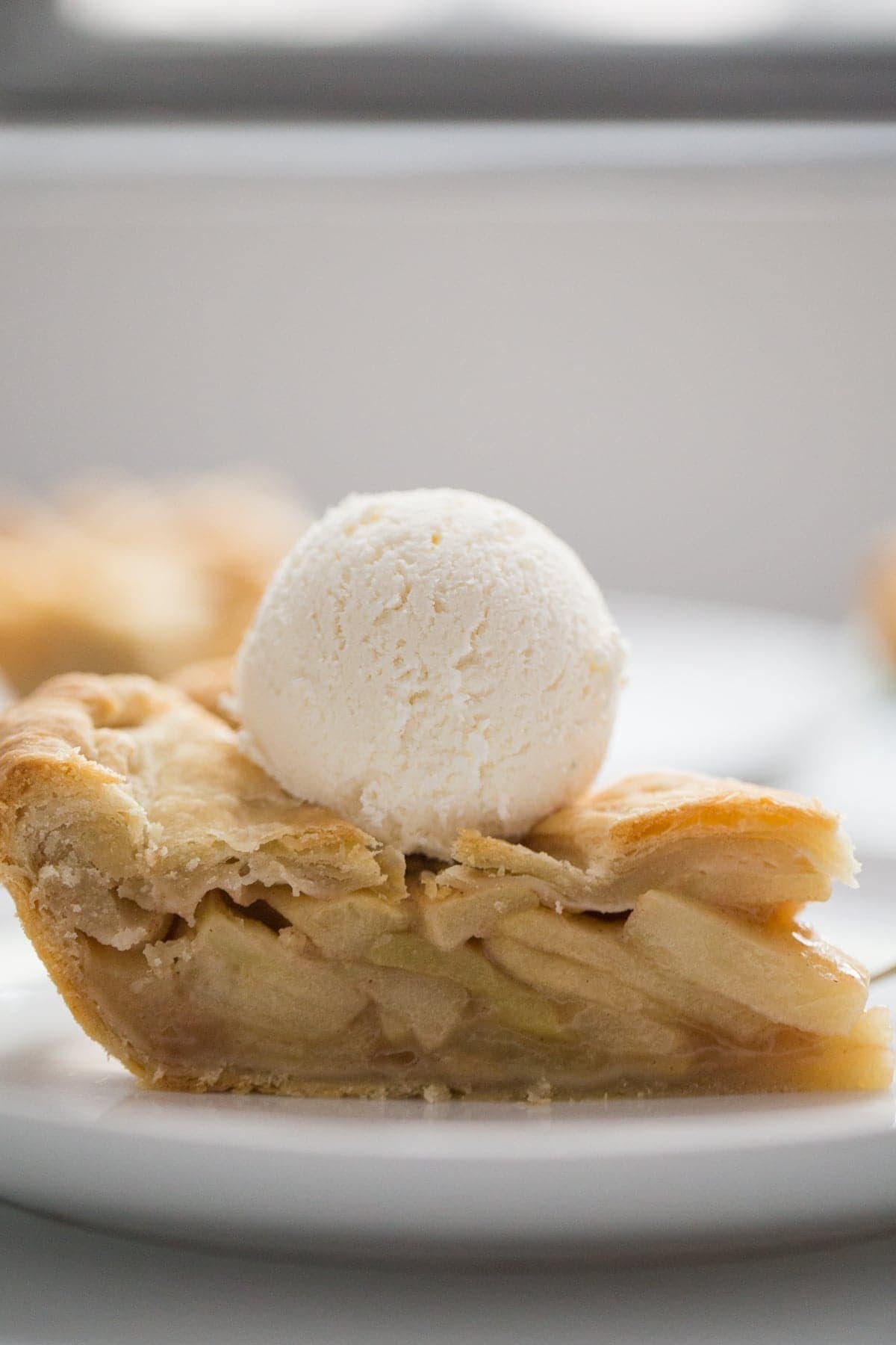A slice of apple pie topped with vanilla ice cream