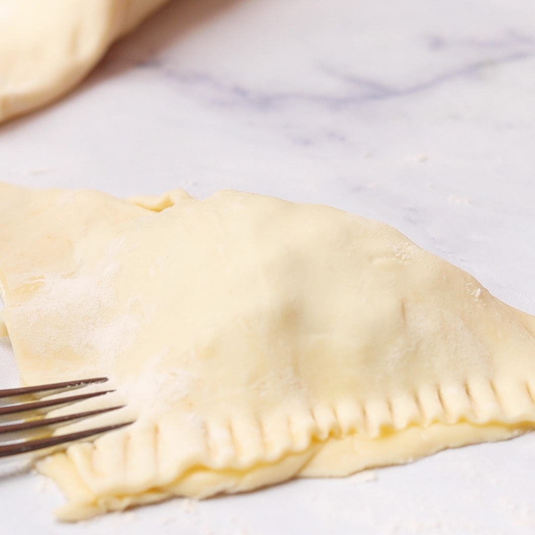 crimping edges of raw Apple Turnover with fork
