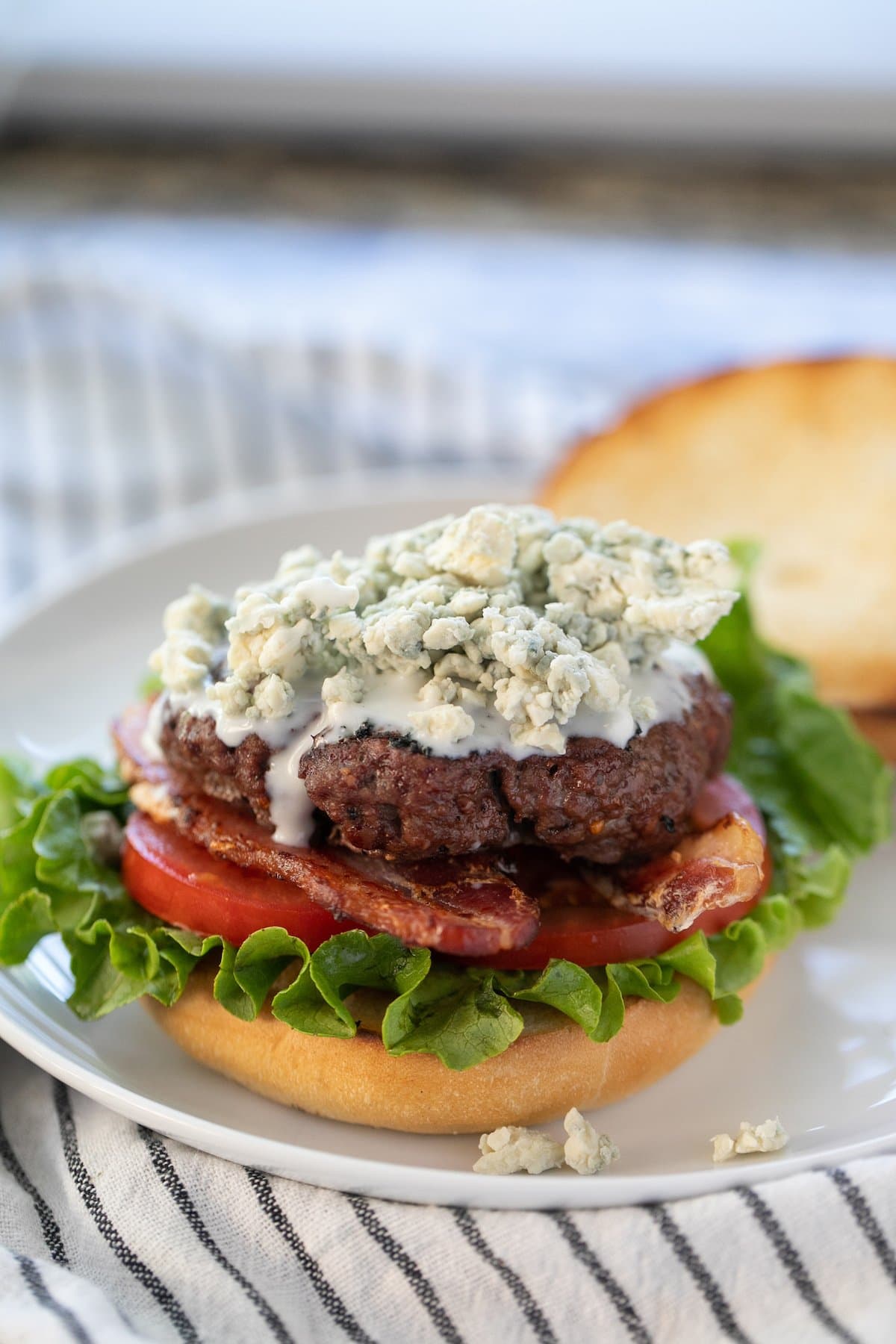 blue cheese burger with the top bun set to the side all on a white plate