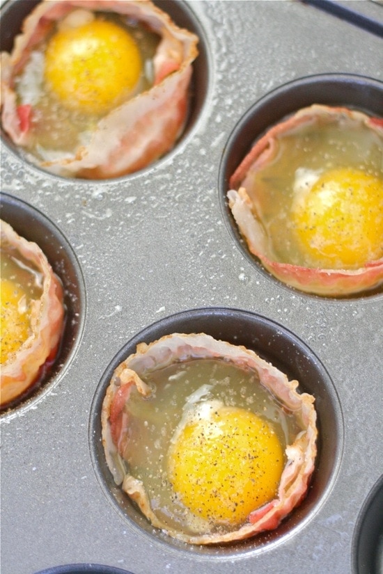 Muffin tins with bacon and raw eggs inside
