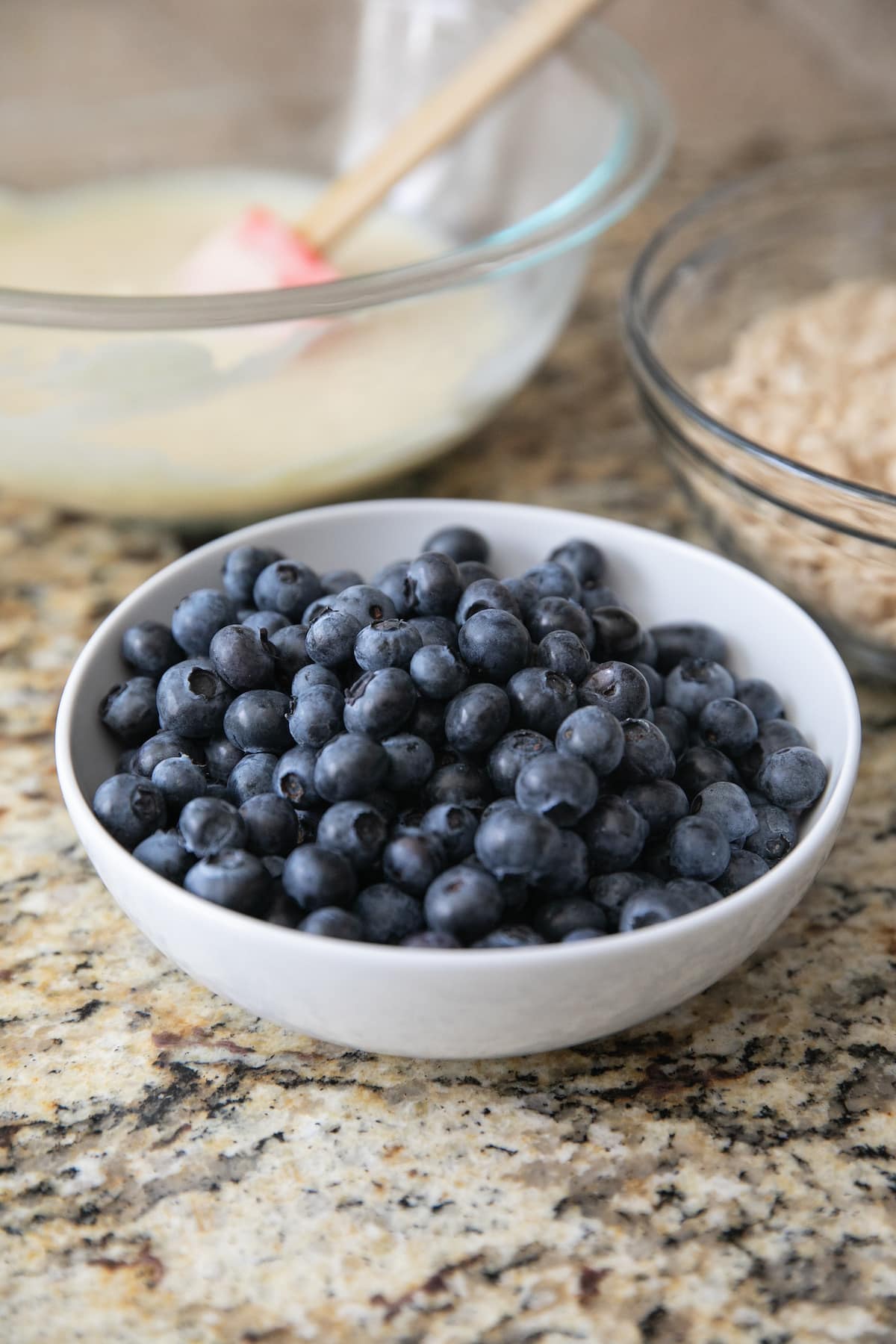 washed room temperature blueberries in a white bowl with two other bowls behind it