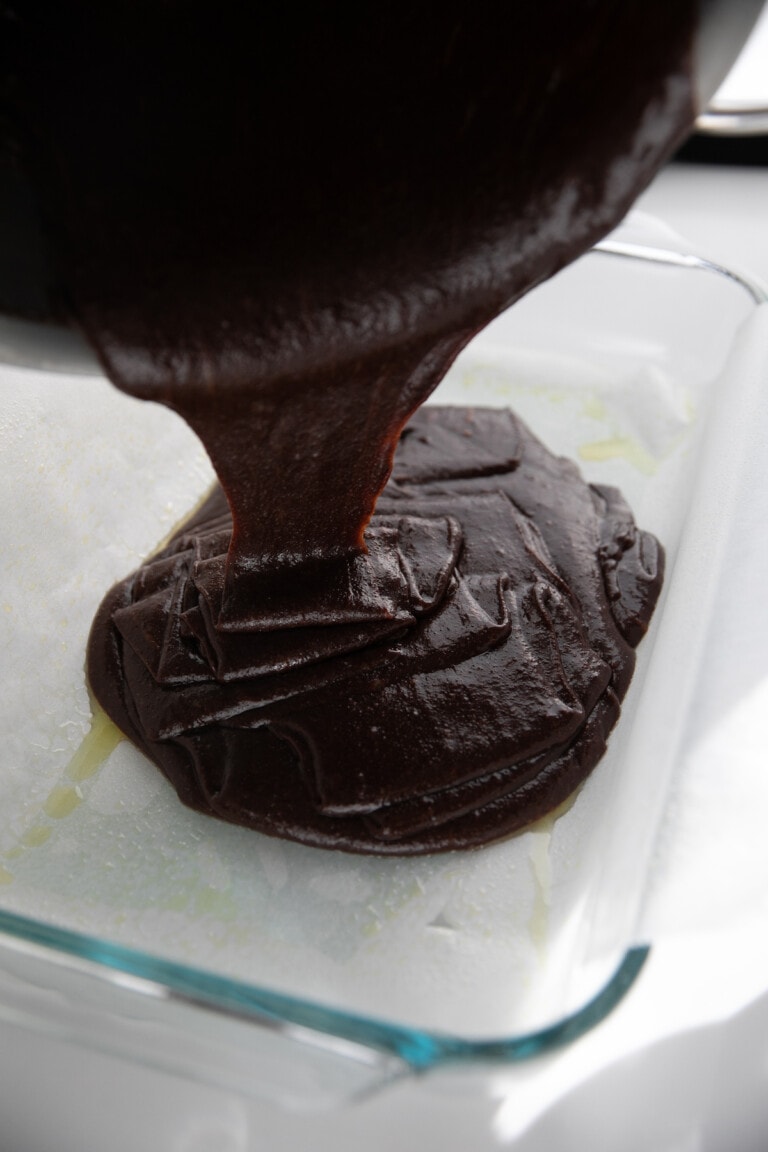 pouring brownie batter into baking pan
