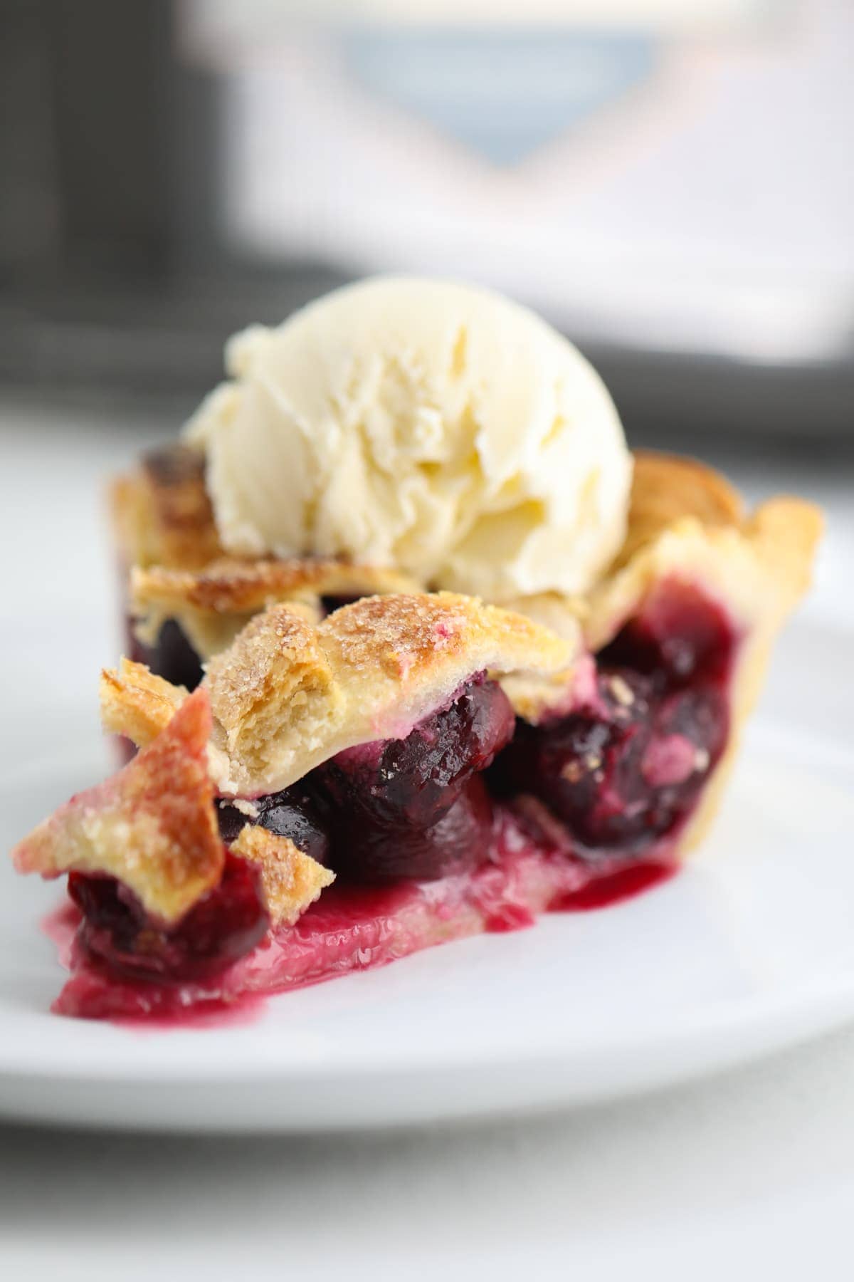 cherry pie on a plate topped with vanilla ice cream