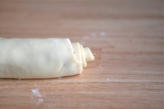 rolling up dough into cinnamon rolls