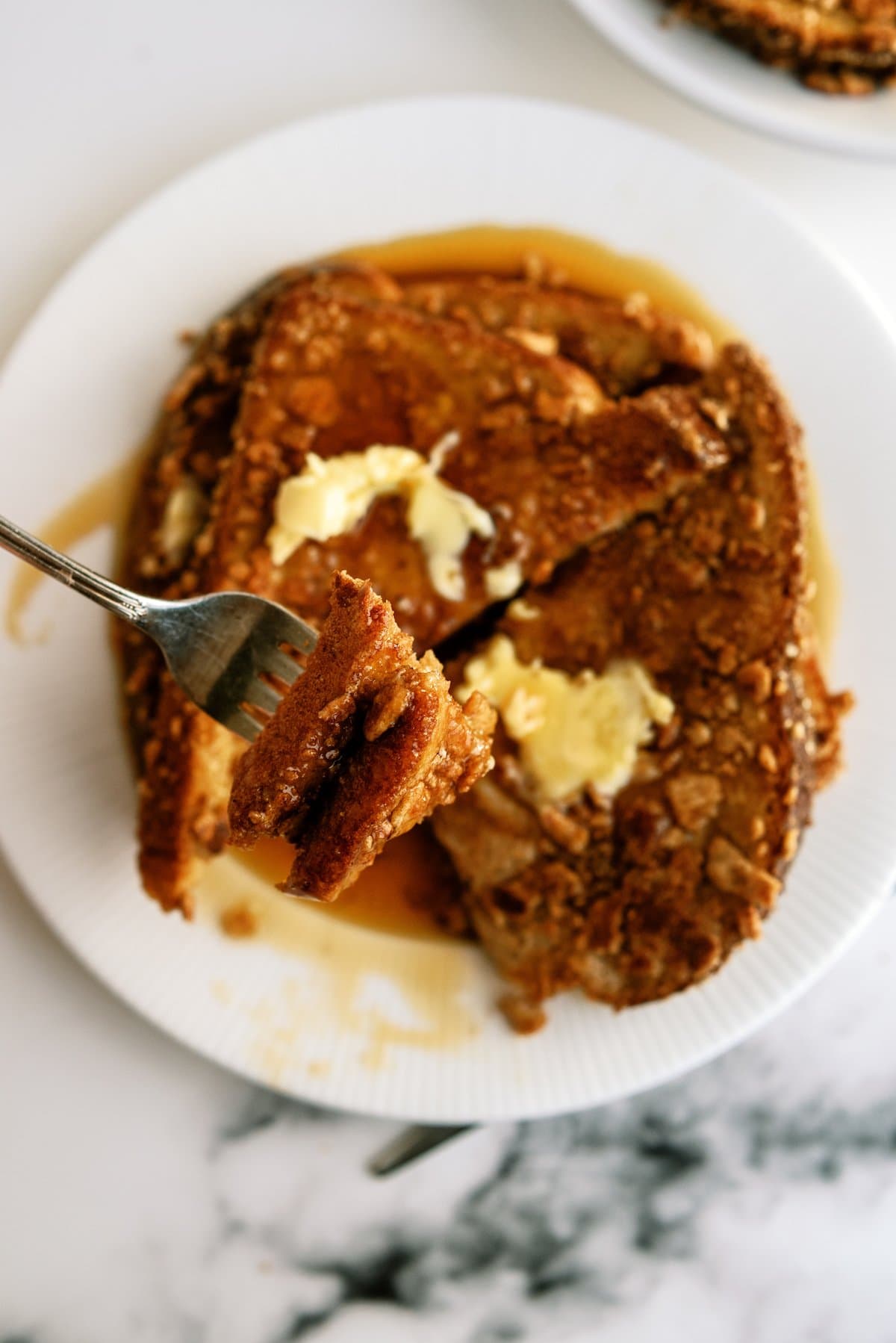 cinnamon encrusted French toast on a plate with a bite on a fork