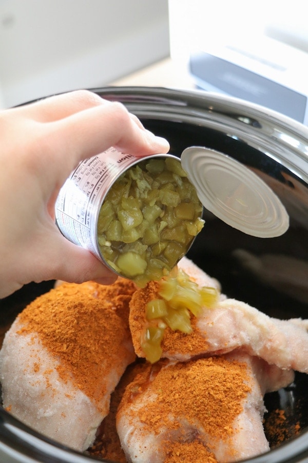 can of chilis being poured onto raw chicken