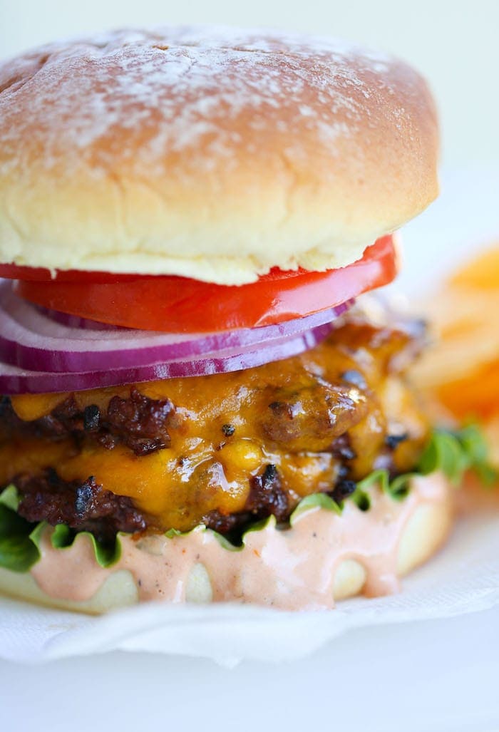 Close up of a homemade Burger on a bun with tomato, red onion, cheese and lettuce