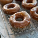 glazed donuts on a cooling wrack about a parchment paper lined baking sheet