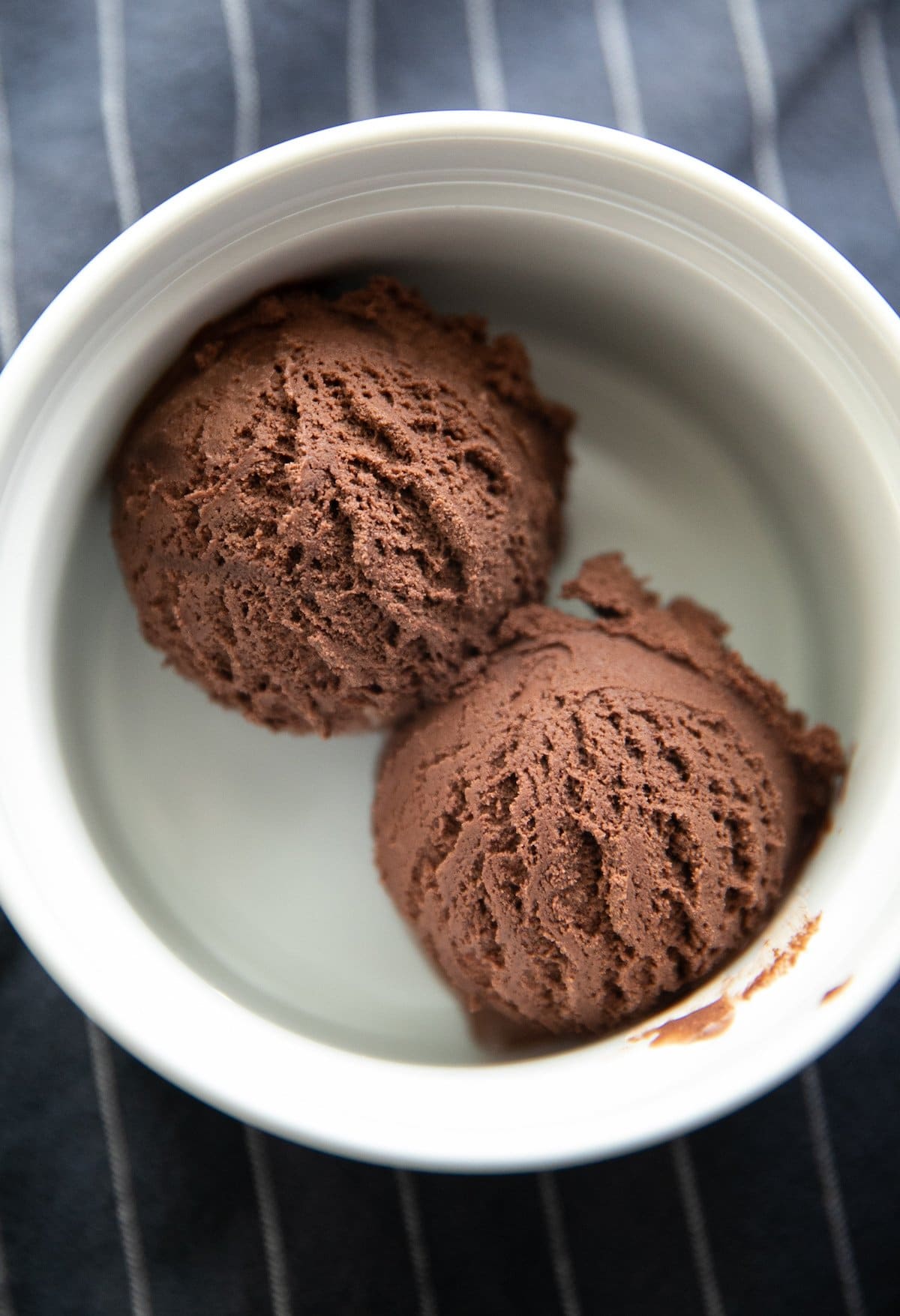 two chocolate ice cream scoops in a white bowl