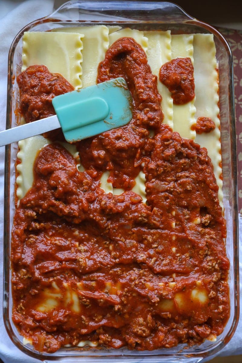 spreading meat sauce layer over pasta