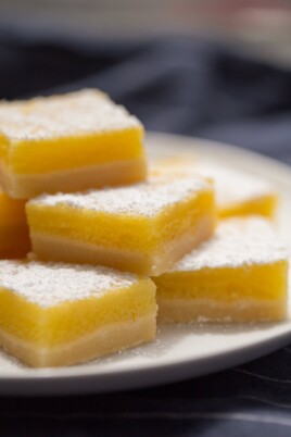 Lemon Bars stacked on top of each other on a white plate