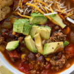 taco soup with avocado and cheese in bowl