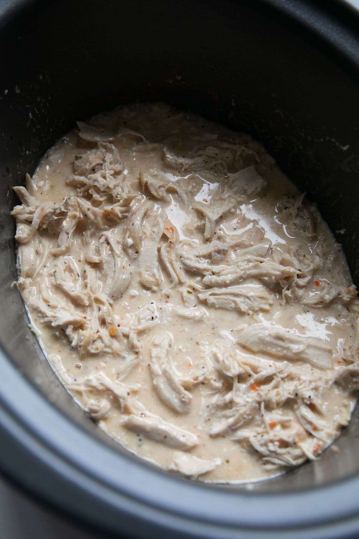 shredded and cooked chicken in sauce in crockpot