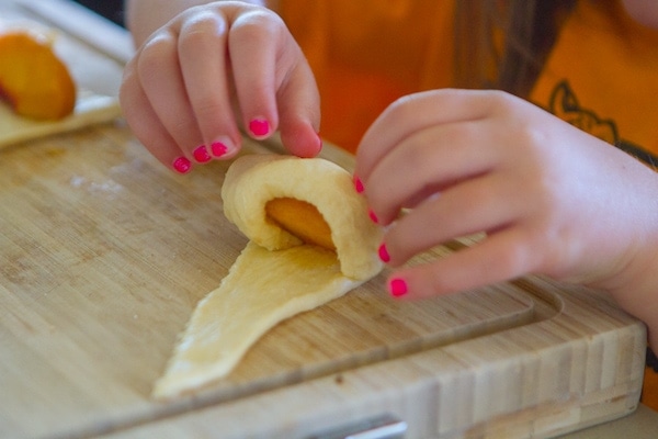Rolling up peach on crescent roll triangle