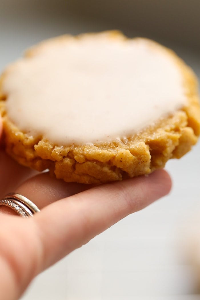 hand holding a pumpkin sugar cookie with icing