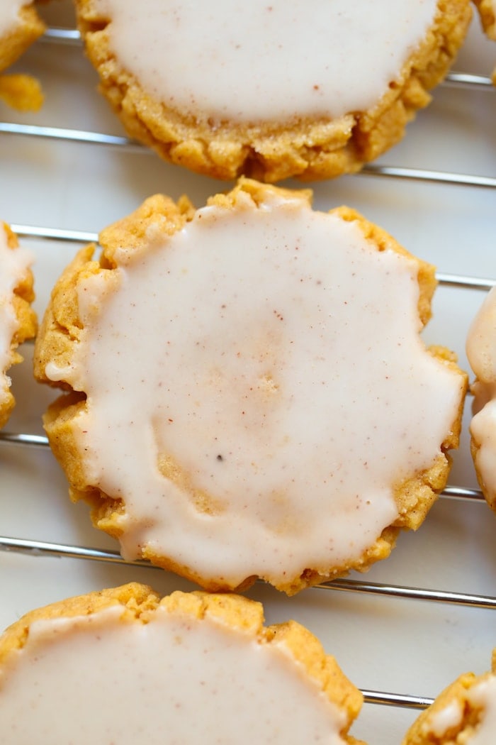 close up of frosted pumpkin sugar cookies on a cooling wrack