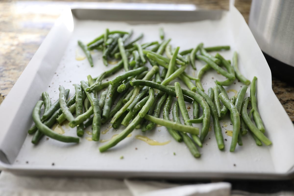 green beans on baking sheet with olive oil, salt and pepper