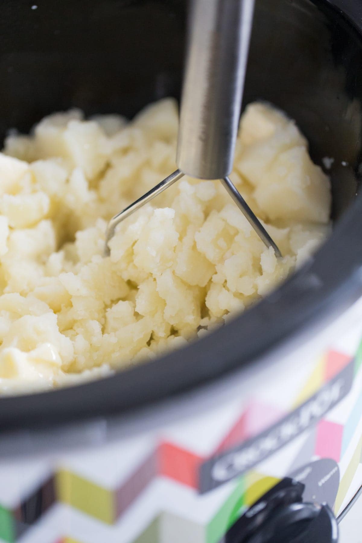 mashing cooked potatoes in a crockpot