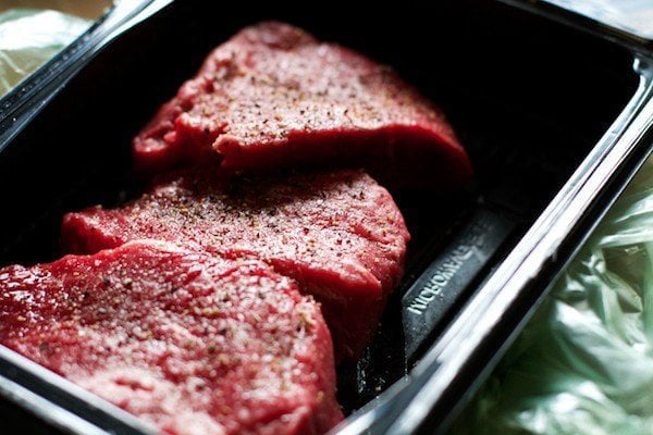 steak in plastic tray with salt and pepper