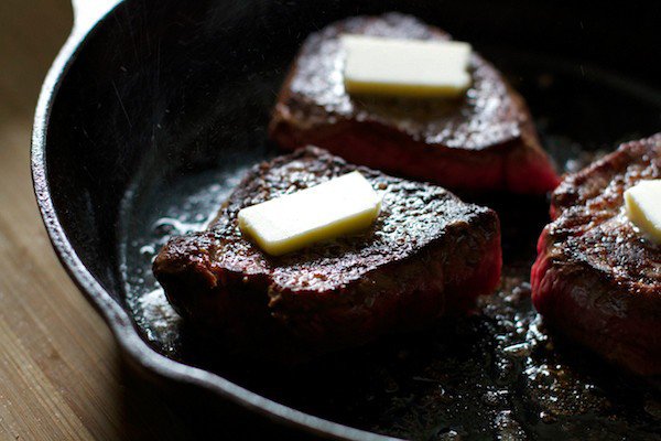 pats of Butter on steak in cast iron skillet