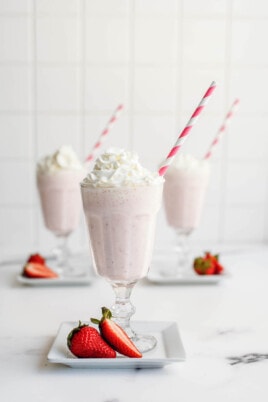 strawberry milkshakes in a glass with straw