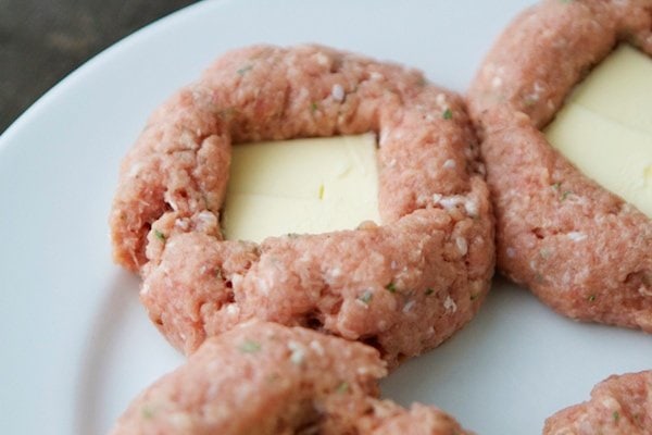 raw turkey patties with a slice of butter placed on top of each one