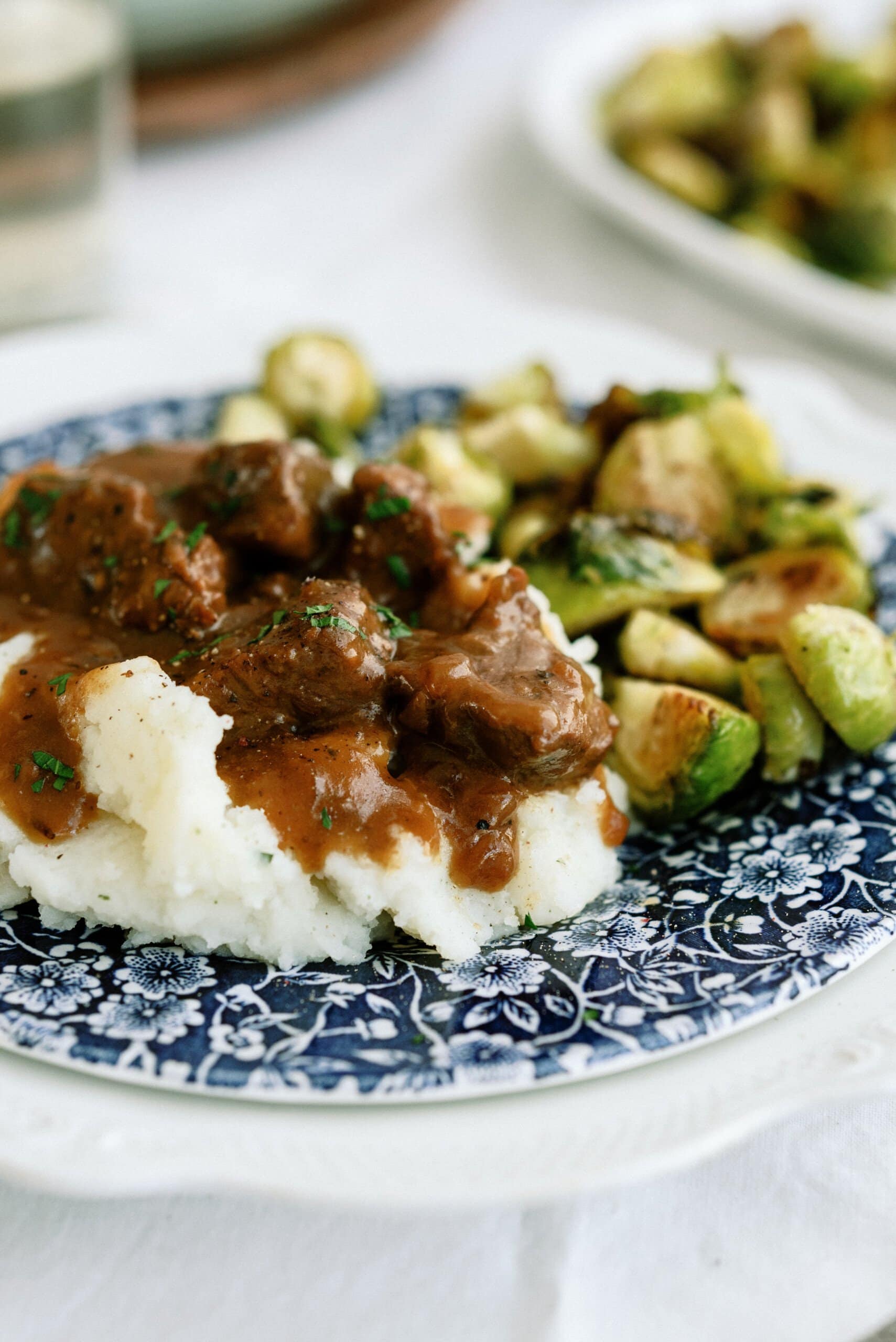 plate with brussel sprouts and mashed potatoes topped with gravy and slow cooked tri tips