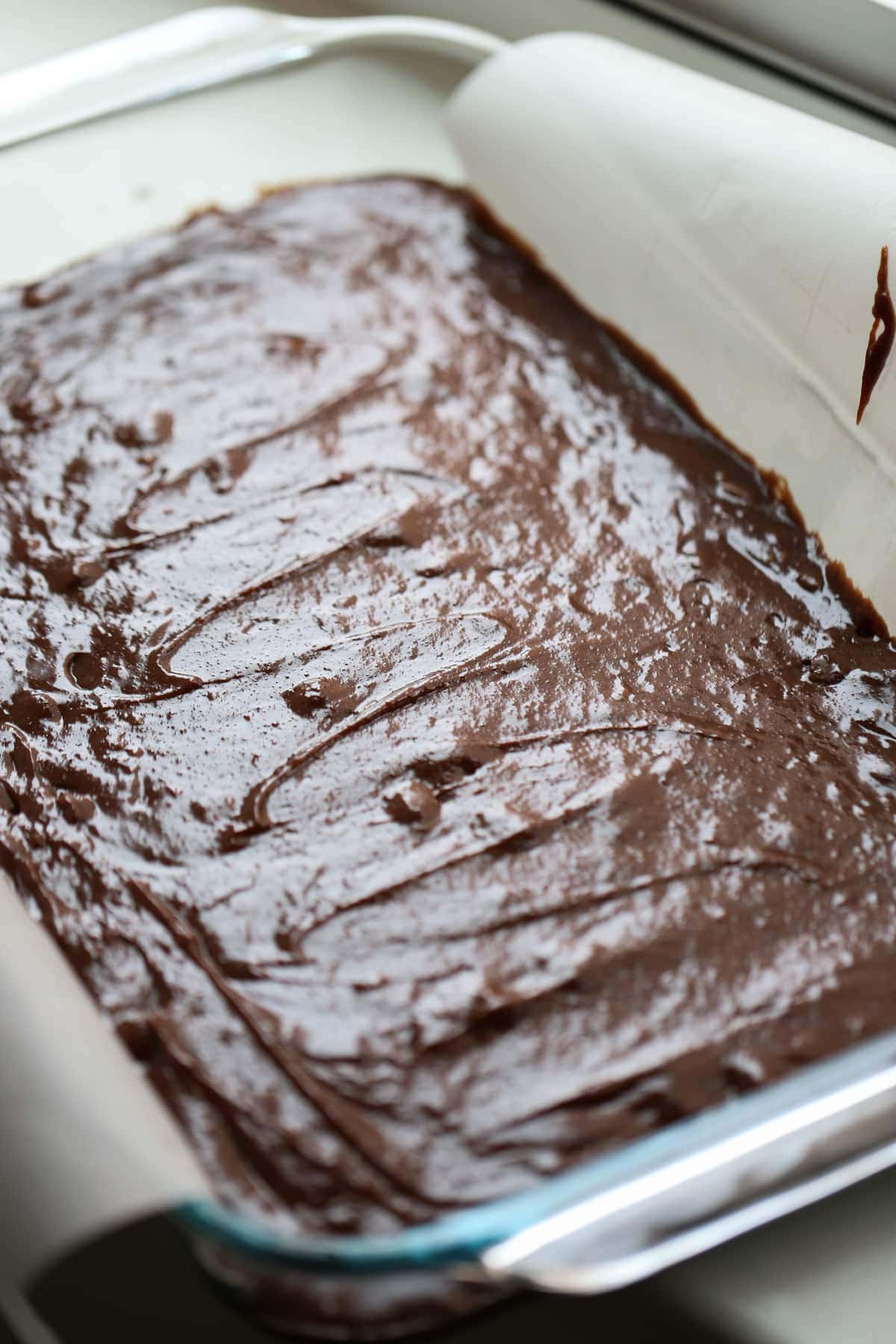 brownie batter in a parchment paper lined glass baking pan