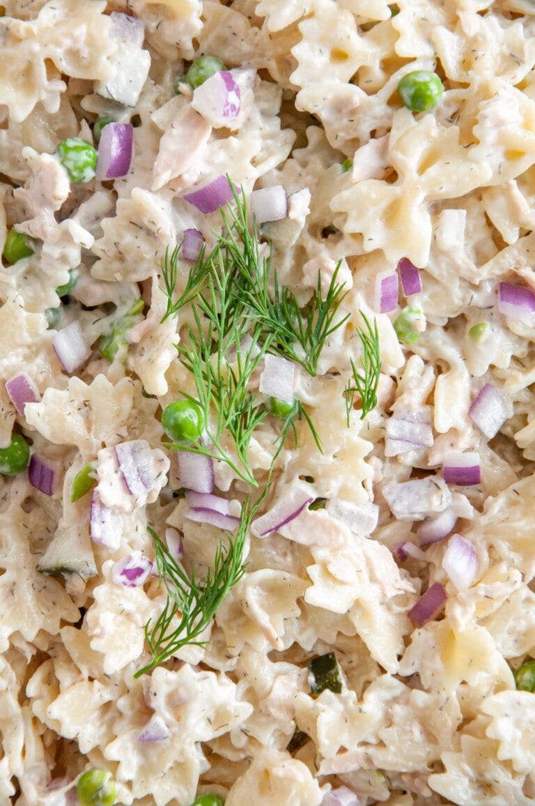 close up of adding dill and red onions to tuna pasta salad