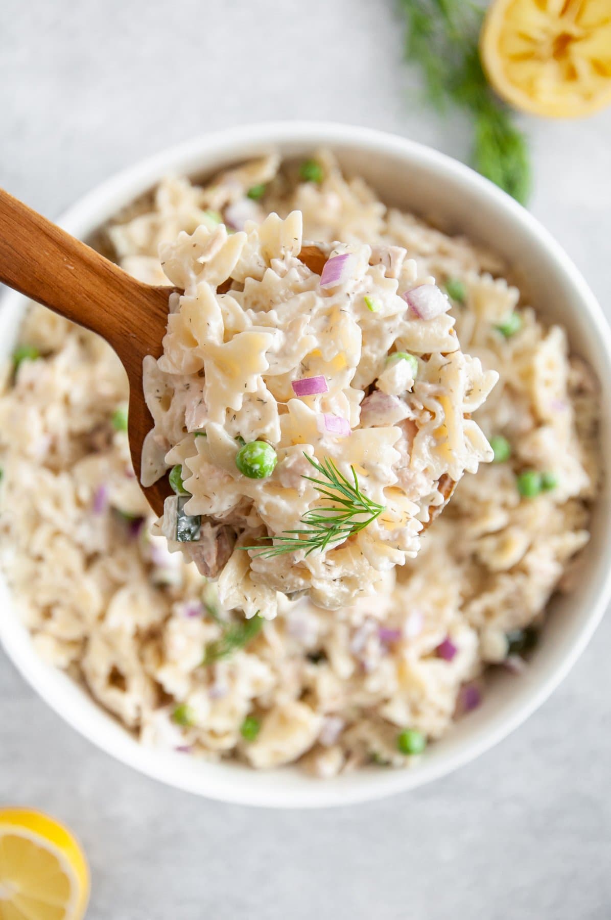 scooping tuna pasta salad out of pit with a wooden spoon