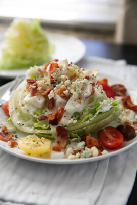 wedge salad with toppings and dressing on a white plate