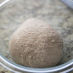 whole wheat pizza dough ball in a glass bowl