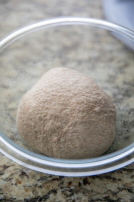 whole wheat pizza dough ball in a glass bowl