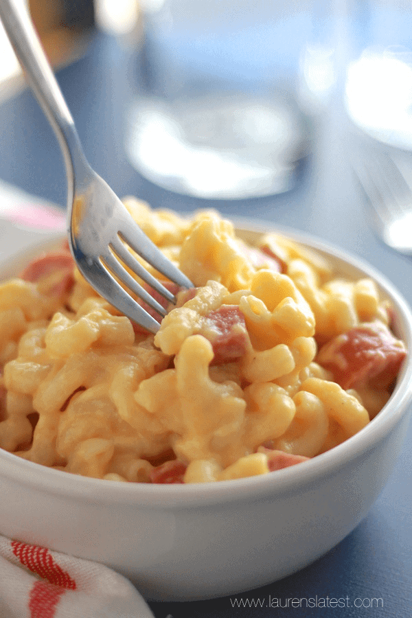 smoked sausage mac and cheese in a white bowl with a fork going to take a scoop